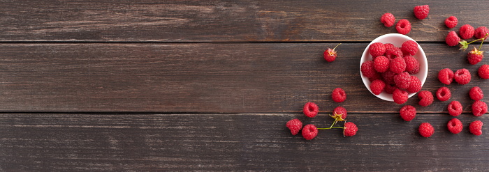 Taste of summer. Ripe fresh raspberries on brown rustic wooden background, top view, panorama with empty space