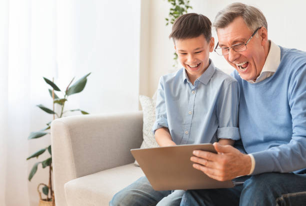 istock Happy Boy And His Grandfather Using Laptop Sitting On Sofa 1193505300