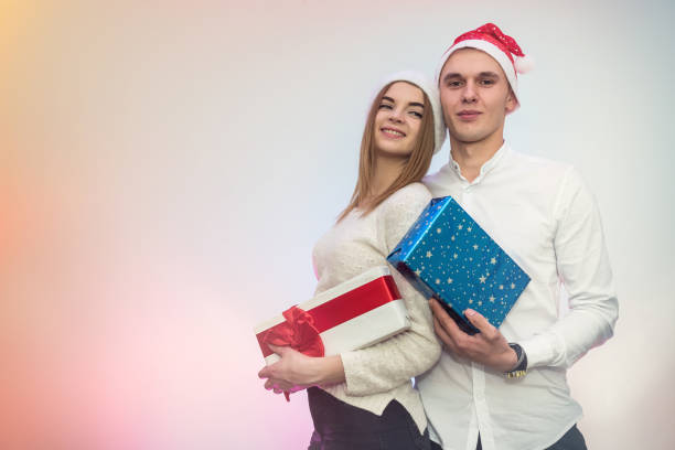 istock Beautiful couple with present box posing in santa hats in studio 1193507525