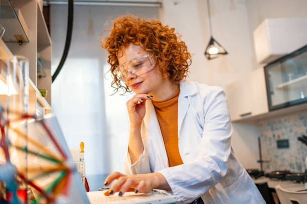 istock Smiling young biochemist using laptop at her desk in laboratory. 1193508083
