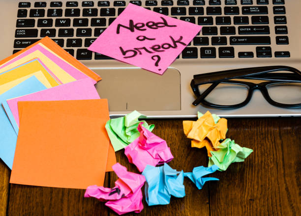 istock Different objects on wooden office desk. Modern wooden office desk table with laptop keyboard, pen, blank colorful sticky notes, black glasses, crumpled paper and post it with question Need a break? 1193509262