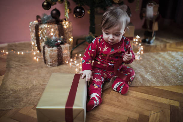 istock Baby boy with Christmas present sitting under Christmas tree 1193510718