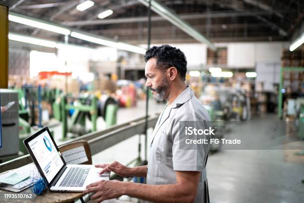 Technician Using Laptop While Working In A Factory Stock Photo - Download Image Now - Manufacturing, Technology, Factory