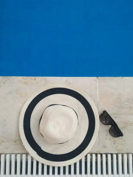 Photo of Straw hat with sunglasses near the pool classic blue color of the year 2020