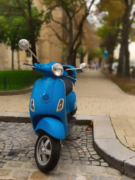 Photo of Retro scooter in classic blue color parked in the city centre