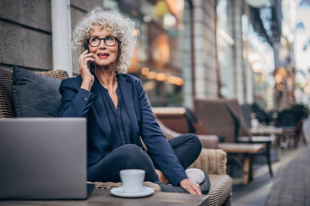 istock Senior lady talking on mobile outdoors in cafe 1193517634