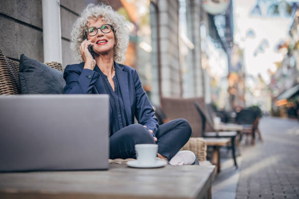 istock Senior woman talking on mobile outdoors in cafe 1193517645