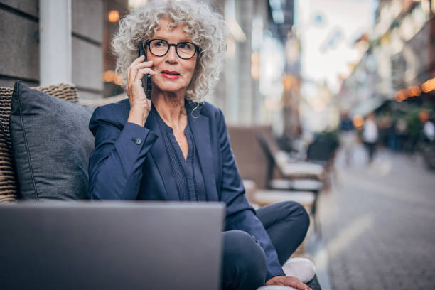 istock Senior lady talking on mobile in sidewalk cafe 1193518610