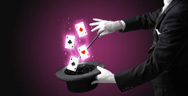 istock Magician making trick with wand and playing cards 1193519096