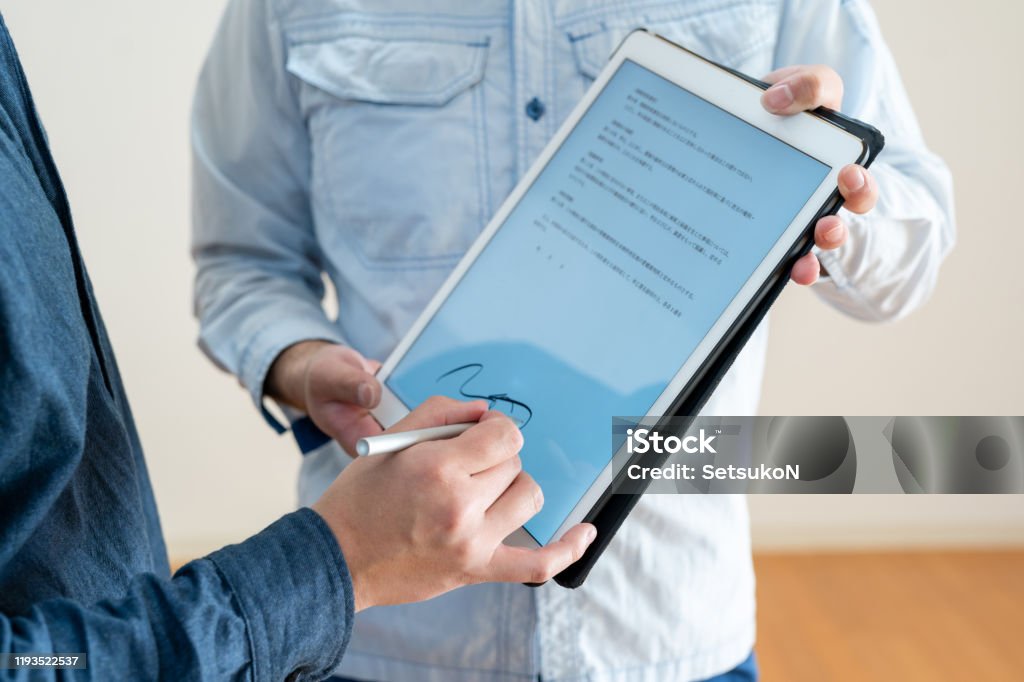 Asian man signing digital contract on tablet, close-up Japanese man signing digital contract on tablet, close-up Contract Stock Photo