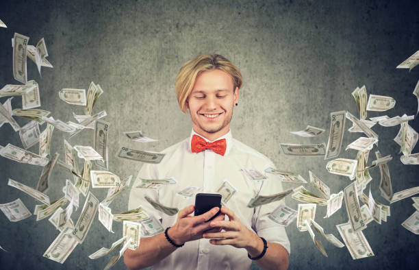 istock Happy man using smartphone with dollar bills flying away from cellphone screen 1193522966