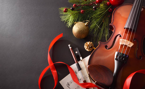 Violin with bow and sheet music on black background elevated Violin with bow and sheet music with Christmas decoration on black background. Christmas festive gift and concert concept. Top elevated view. Horizontal composition. conservatory education building stock pictures, royalty-free photos & images