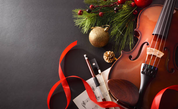 Violin with bow and sheet music on black background elevated Violin with bow and sheet music with Christmas decoration on black background. Christmas festive gift and concert concept. Top elevated view. Horizontal composition. traditional song stock pictures, royalty-free photos & images