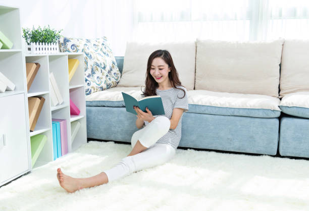 istock Beautiful woman sitting on floor reading book 1193530998