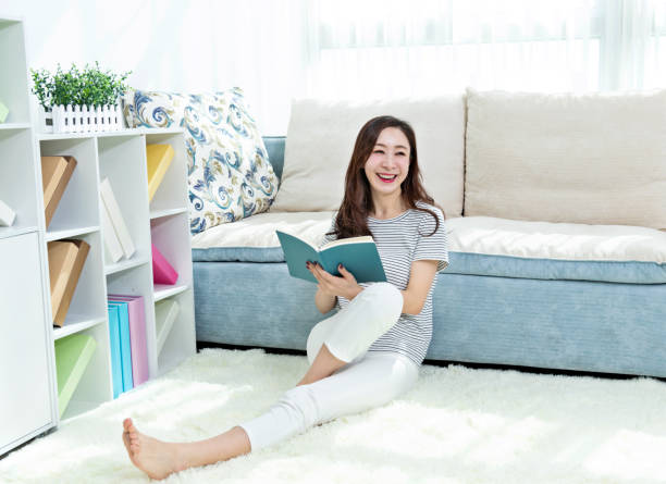 istock Beautiful woman sitting on floor reading book 1193531116