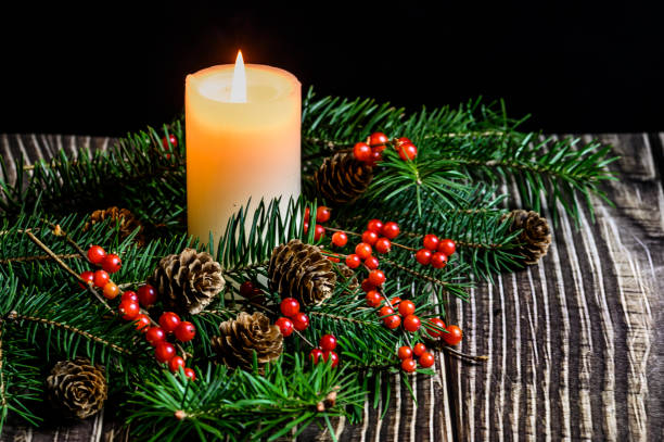 istock Christmas tree, red berries and burning white candles on a wooden table 1193532275