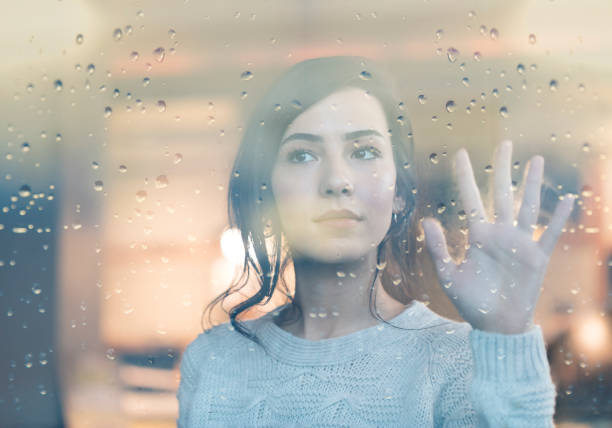 istock Thoughtful Young Woman Looking Through Window With Raindrops 1193533936