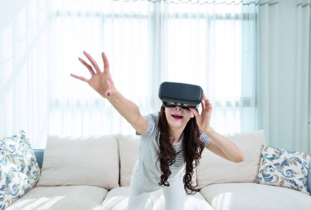 istock Woman wearing virtual reality simulator at home 1193535064