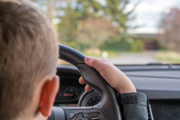 Child drives daddy's car on a street Child at the wheel of a car discover card stock pictures, royalty-free photos & images