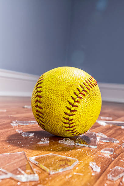istock A yellow softball sitting with broken glass from a window on the floor 1193537646