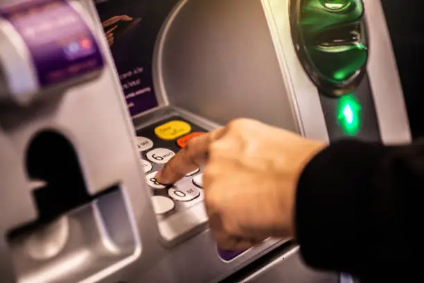 Photo of A man hand dials a personal code on the ATM keyboard.