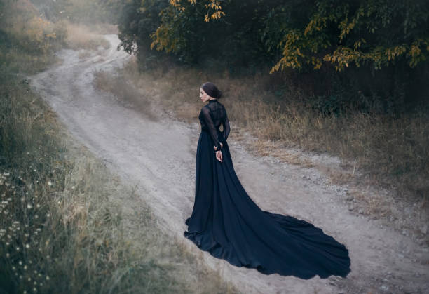 signora gotica dal vecchio film horror. cammina lungo la strada nella foresta autunnale. - women gothic style sensuality mystery foto e immagini stock