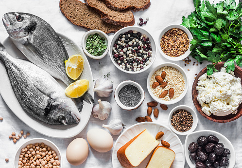 Products rich in calcium - fish seafood, cottage cheese, garlic, poppy seeds, nuts, sesame, cheese, beans, eggs on a light background, top view. Balanced food background