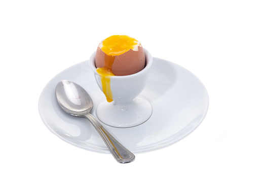 Boiled egg on a white plate with a spoon - white background