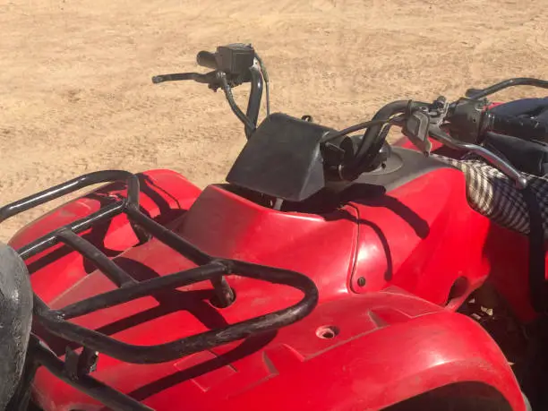 Elements of a motobike for tourist adventures in the desert. View from the front red plastic steering knob. Luggage space.