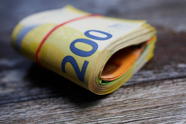 macro color photo of two hundred Euro banknotes against wooden surface, bound with a household rubber