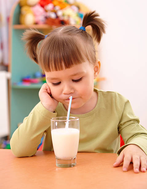 Gloomy little girl drinks milk stock photo