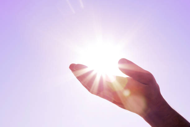 A DSLR photo of a male hand as if holding the sun with beautiful sunbeams. Space for copy.
