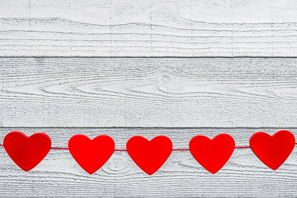 istock Red heart shapes hanging on a string against a white wood background 1193548553