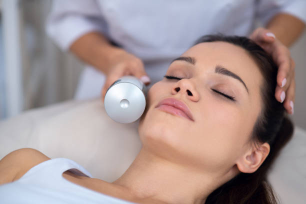 istock Young woman closing eyes while having ultrasound face massage 1193548558