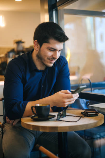 istock Businessman using smart phone and drinking coffee in cafe 1193550209