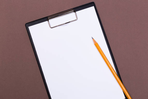 istock Clipboard with white sheet and pen on a colored background. View from above. space for text 1193551703