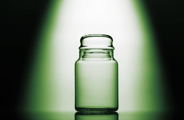 Empty glass jar on a green, black and white background with light effect