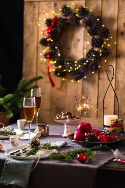 istock Decorated Christmas or New year dinner table setting, wooden wall with pine cone wreath, bokeh background, basket of fir branches 1193563439