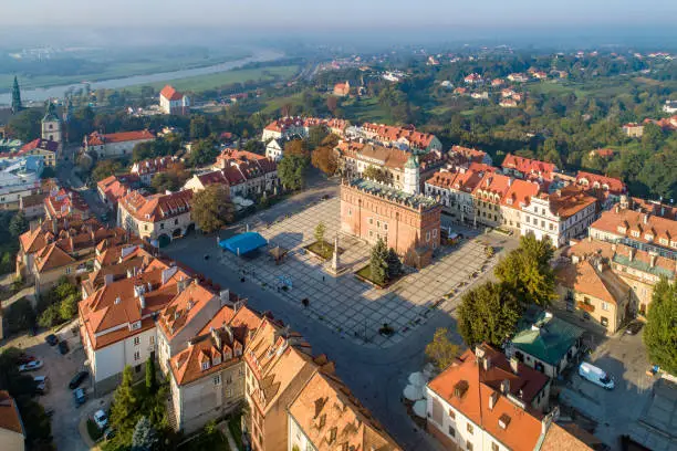 Aerial skyline panorama of Sandomierz old city, Poland, in sunrise light. Old town with market square, Gothic city hall, medieval castle on the left and Vistula River in morning fog in the background