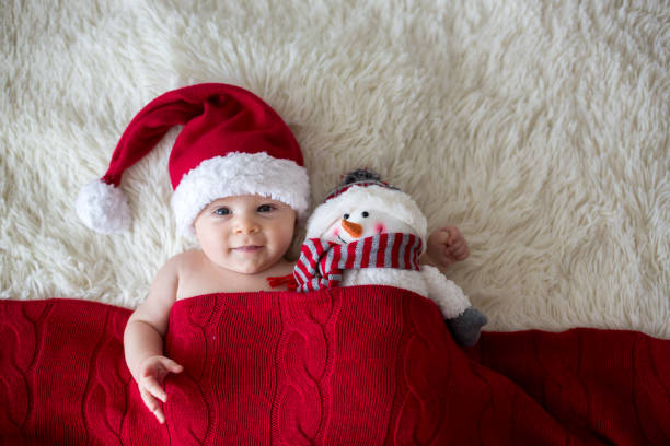 Christmas portrait of cute little newborn baby boy, wearing santa hat Christmas portrait of cute little newborn baby boy, wearing santa hat and hugging little cute snowman toy, studio shot, winter time crochet photos stock pictures, royalty-free photos & images
