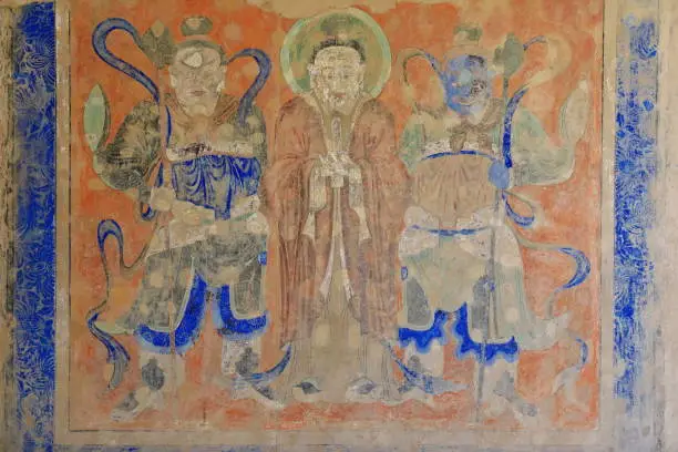 The Buddha between Vaisravana -left- and Virudhaka -right- two of the Four Heavenly Kings guardians of the N.and S.respectively. Mural fresco on the outer wall of the Mogao caves-Dunhuang-Gansu-China.