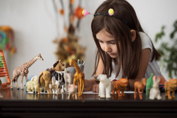 小女孩非常專注于她的動物玩具 - 動物像 個照片及圖片檔
