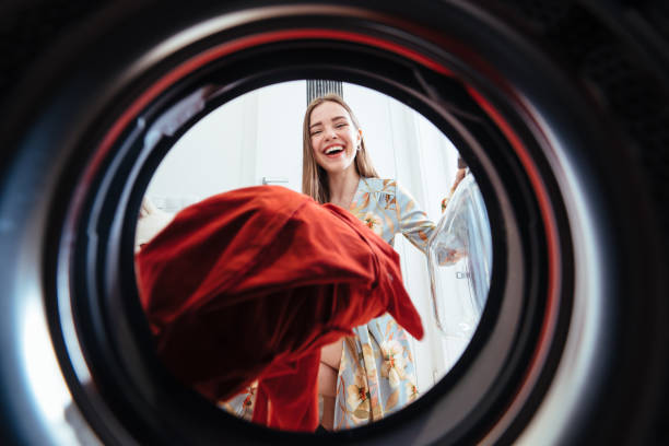 Young woman at home puts the dress in the drying machine. stock photo