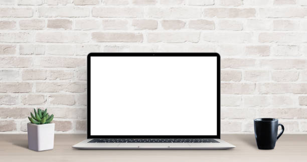istock Laptop mockup on simple, clean desk with brick wall in background. Isolated screen for ap, web site resentation. Plant and cup of coffee on table 1193570267