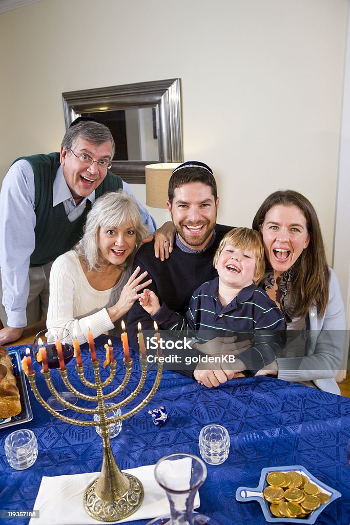 Smiling Jewish family celebrating Chanukah Jewish family celebrating Chanukah at table with menorah Family Stock Photo
