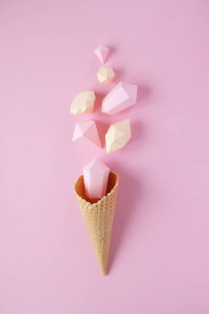 istock Hand holds a waffle cone with paper diamonds on pink background. Holiday concept. 1193572577
