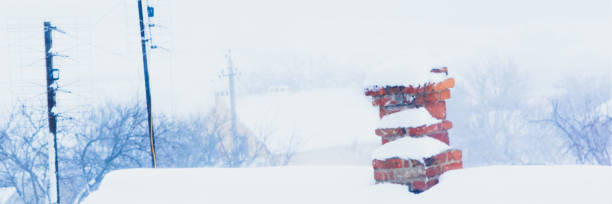 istock Chimney in red bricks and antennas with white snow on rural roof. 1193573524