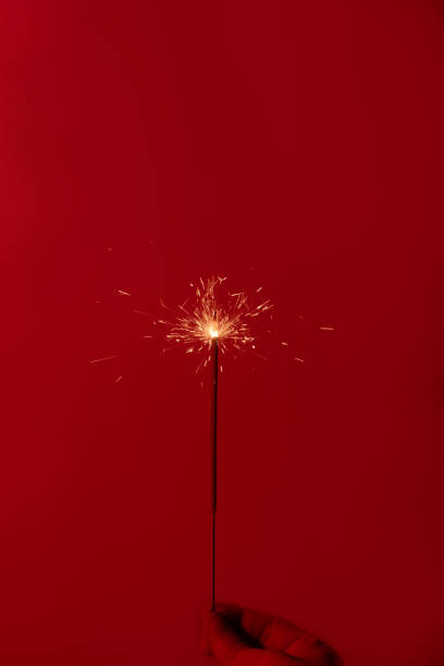 istock sparkler on a red background. Short shutter speed. Small sparks scatter in different directions. 1193574144