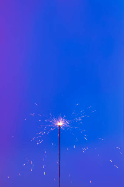 istock sparkler on a blue background. Short shutter speed. Small sparks scatter in different directions 1193574149