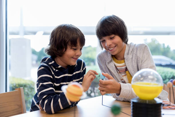 istock Brothers goof around with solar system model at library 1193583427